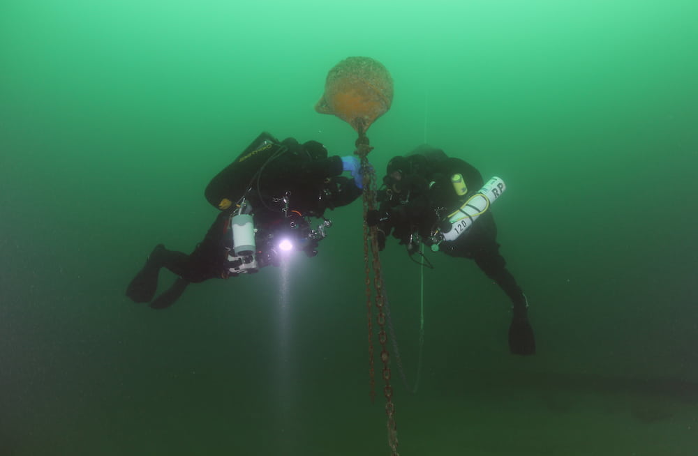 Divers holding on to a mooring buoy